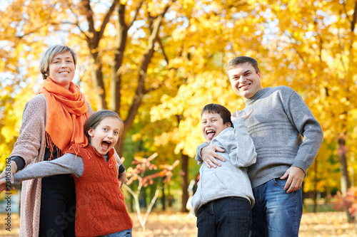 Happy family walks in autumn city park. Children and parents posing, smiling, playing and having fun. Bright yellow trees.