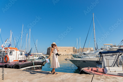 Elegant young tourist visitor woman walking on a sightseeing tour at Heraklion Venetian port, Crete, Greece