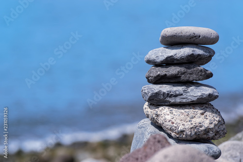 Close-up of stacked stones against coastline and blue water