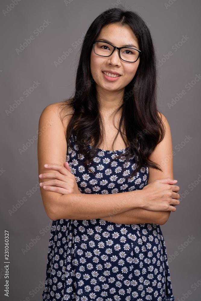 Asian woman wearing eyeglasses against gray background Asian woman wearing eyeglasses against gray background