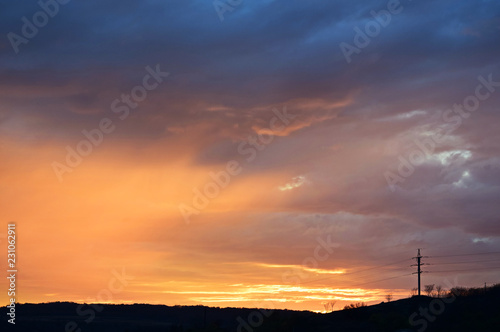 Colorful fiery sunset over dark landscape. Natural scenery, beautiful view. Copy space.