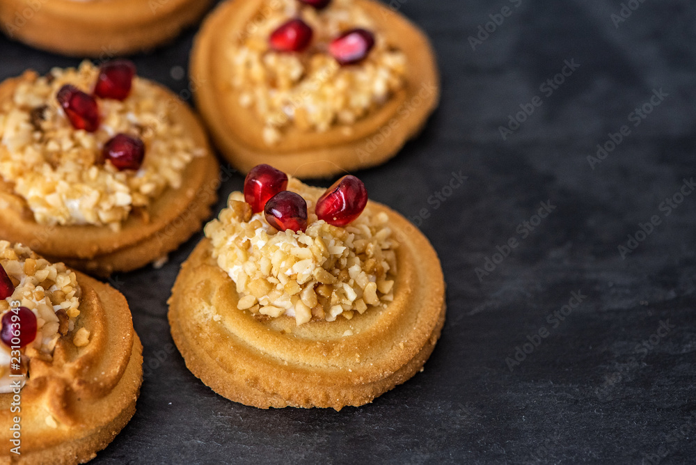 Sweet dessert. Cream cookies sprinkled with nuts and garnished with pomegranate seeds. Close Up Sweet dessert. Cream cookies sprinkled with nuts and garnished with pomegranate seeds. Close Up
