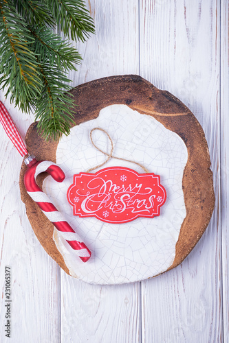Merry Christmas! Christmas decorations glass candy cane, ceramic plate and christmas tree branch on a white background