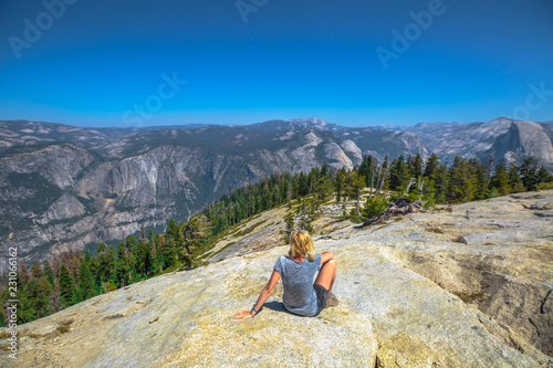 Hiking woman relaxing sitting at Sentinel Dome summit of Yosemite National Park. Happy after hiking and enjoying El Capitan view at Sentinel Dome. Summer travel holidays in California, United States.