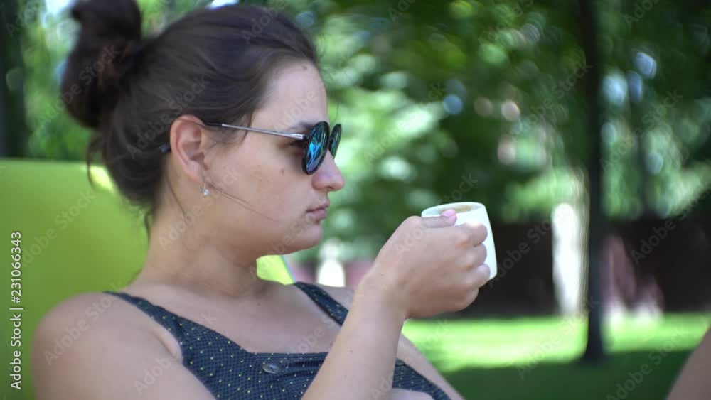 Woman drinking coffee while lying on sunbed in luxury garden. Woman drinking coffee while lying on sunbed in luxury garden.
