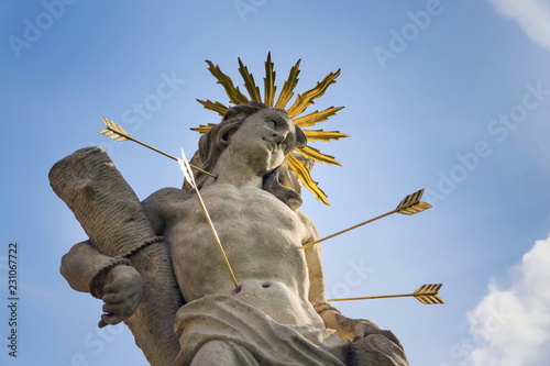 Saint Sebastian shot with arrows martyr statue, Marian plague column of Saint Rosalia, Velehrad Monastery, Moravia, Czech Republic, sunny day clear blue sky photo