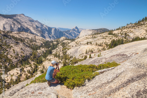 Trekking traveler photographer shooting the Half Dome on Olmsted Point. Tioga Road in Yosemite National Park, California, USA. Nature photographer taking pictures outdoors during hiking travel.
