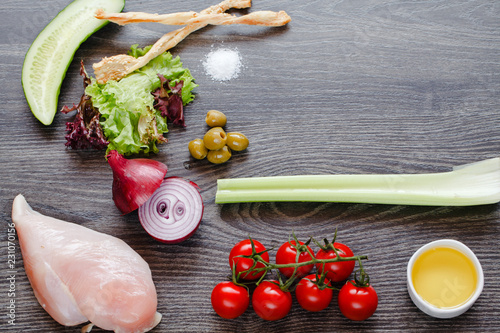 ingredients for cooking, chicken breast and vegetables on a wooden table