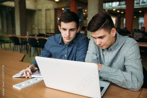 Two friends student use laptop in library