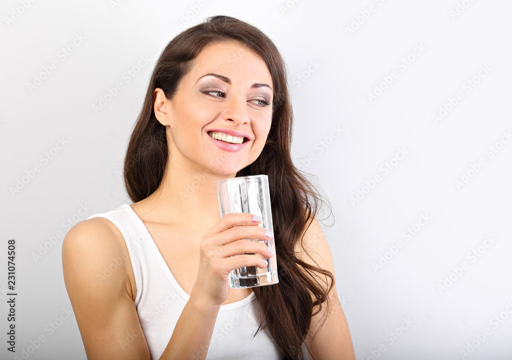 Positive happy woman with healthy skin and long curly hair drinking pure water on white background with toothy smile Positive happy woman with healthy skin and long curly hair drinking pure water on white background with toothy smile