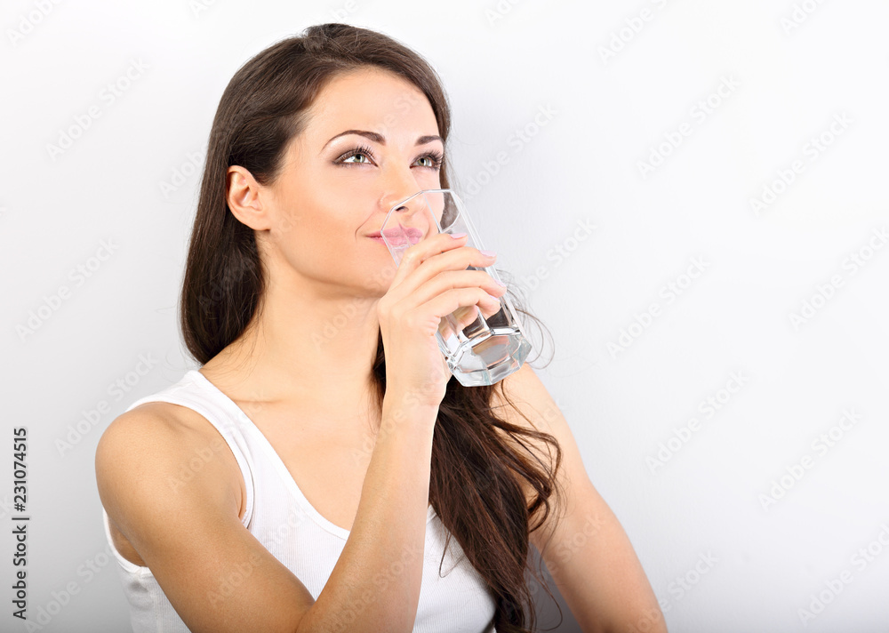 Positive happy smiling woman with healthy skin and long curly hair drinking pure water on white background. Closeup portrait Positive happy smiling woman with healthy skin and long curly hair drinking pure water on white background. Closeup portrait