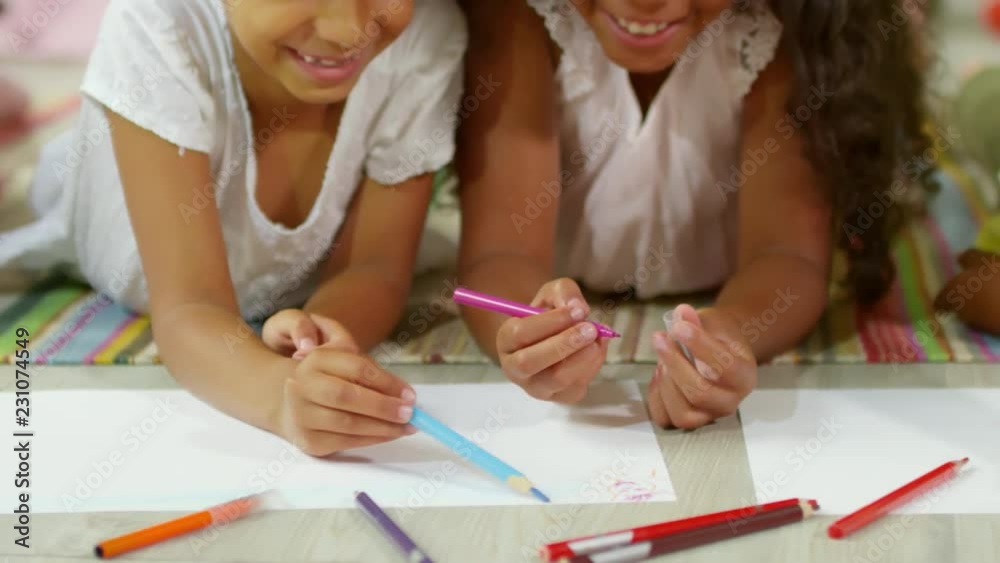 Tracking shot of group of black children lying on floor and drawing pictures together with colored pencils, close up Tracking shot of group of black children lying on floor and drawing pictures together with colored pencils, close up