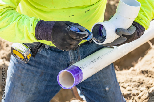 Картината върху платно Plumber Applying Pipe Cleaner, Primer and Glue to PVC Pipe At Construction Site