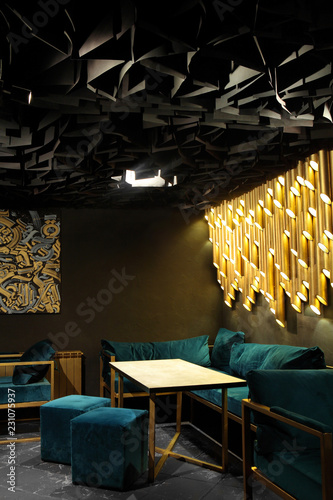 Modern lounge bar interior.Dark tone.Dark cyan sofa and chairs.Golden laterns in form of tubes. photo