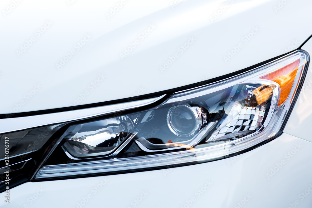 car headlight close up, xenon light with lens on a white car.