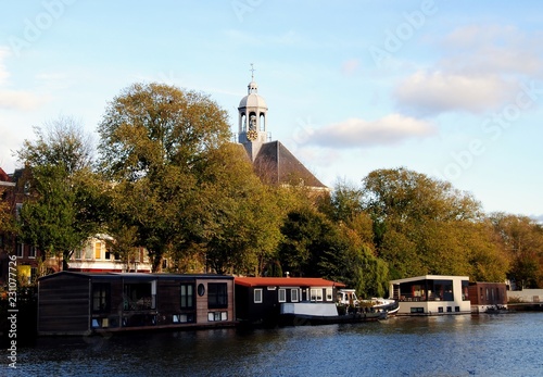 Amsterdam, view on the  Nieuwe Vaart with houseboats and the tower of the Oosterkerk (Eastern church), 1669-1671  behind a row of trees photo