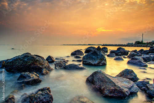 A long exposure picture Beautiful Scenery cloudy Sunset With Stone and wave As Foreground