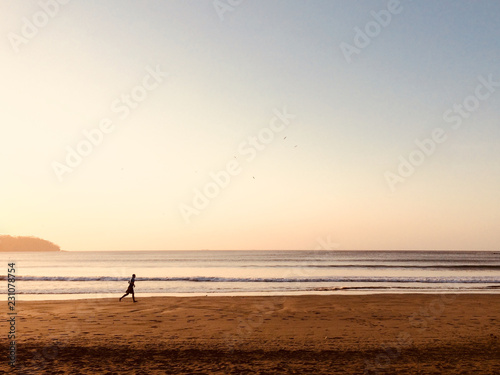person running on beach during sunset - jogger at ocean