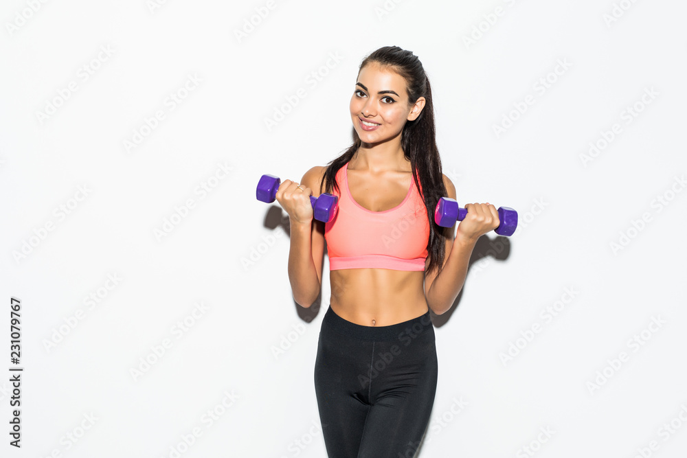 Portrait of young pretty woman holding weights and doing fitness against a white background Portrait of young pretty woman holding weights and doing fitness against a white background