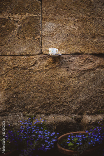 taza colgada en la parez con flores moradas photo