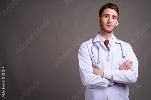 Young handsome man doctor against gray background © Ranta Images