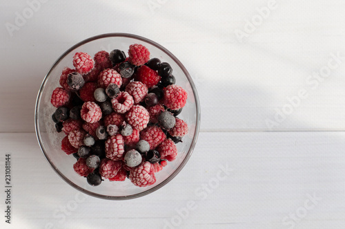 the frozen berries raspberry and currant in a glass plate on a white background