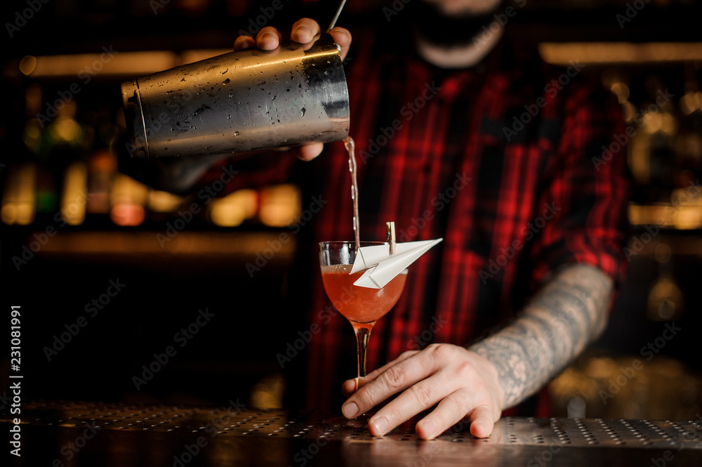 Bartender pourring an alcoholic drink making cocktail in the glass