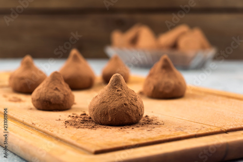 Chocolate truffles sprinkled with cocoa powder on a wooden kitchen Board.