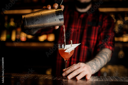 Bartender pourring an alcoholic drink making cocktail in the glass