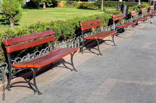 Fotografija a row of benches on the pedestrian sidewalk in the park area of the city, empty wooden benches nobody