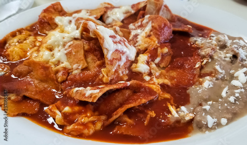 Delicious chilaquiles, typical Mexican food with beans, cheese and hot tomato sauce over traditional tortilla.