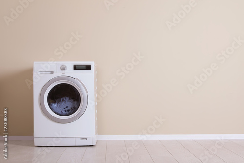 Washing machine near color wall, space for text. Laundry day