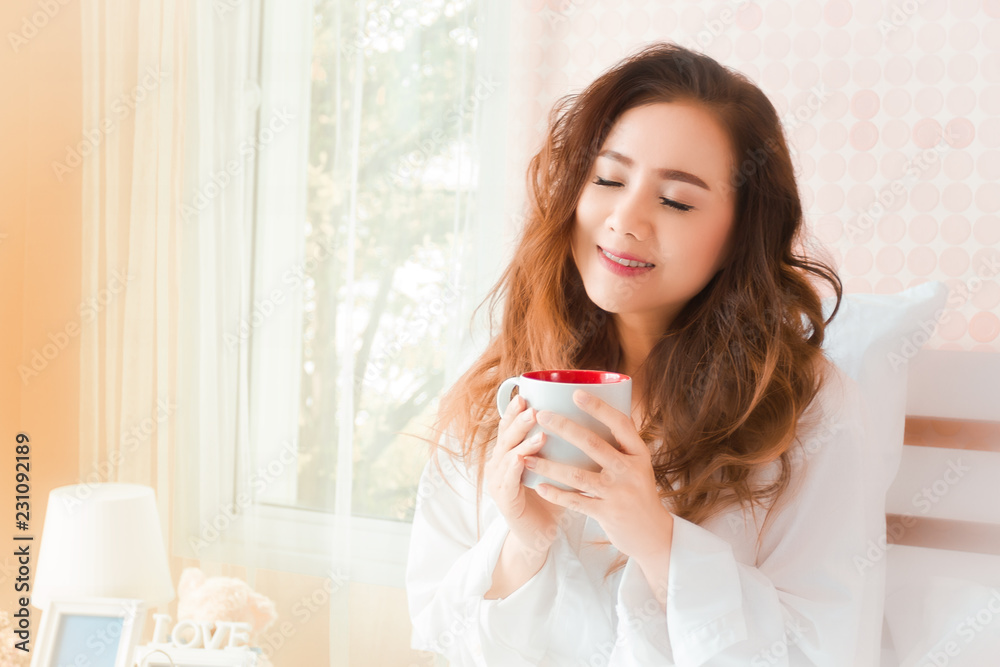 Young woman holding and smell coffee on the bed Young woman holding and smell coffee on the bed