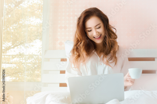 Young beautiful woman working with laptop in bedroom