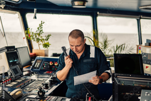 Marine navigational officer is reporting by VHF radio during navigation watch. Bridge GMDSS watch photo