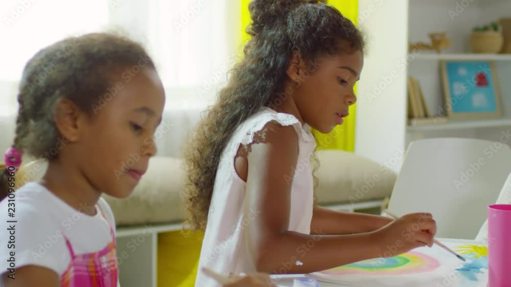 Medium shot of group of cute black children using paint brushes and watercolor to draw beautiful pictures in art class at school or in kindergarten Medium shot of group of cute black children using paint brushes and watercolor to draw beautiful pictures in art class at school or in kindergarten