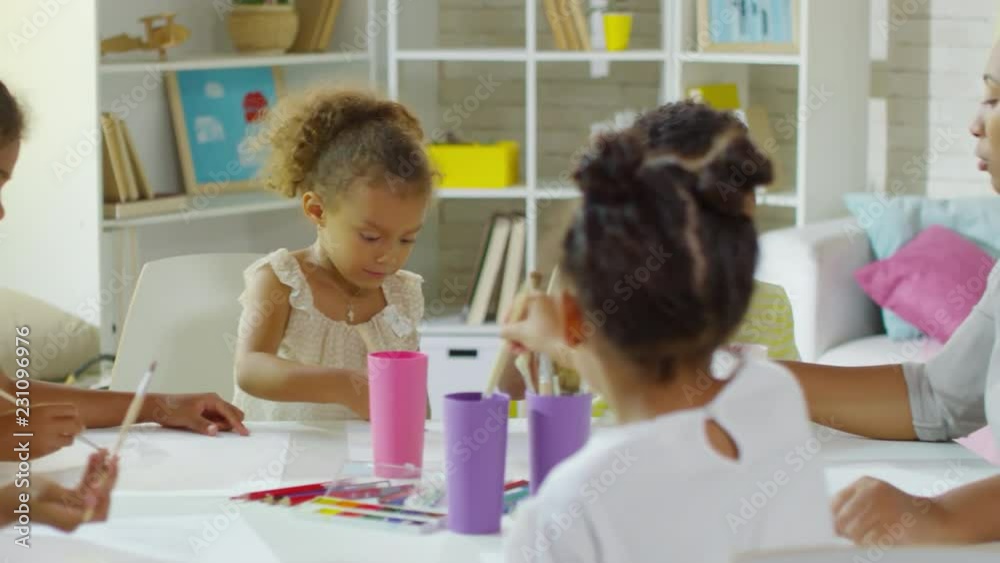 Dolly shot of cute black children of elementary school age using watercolor to draw pictures in art class Dolly shot of cute black children of elementary school age using watercolor to draw pictures in art class