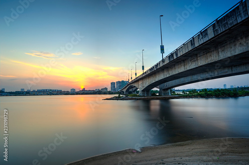 A long exposure picture of beautiful burning sunset and blue hour under the bridge