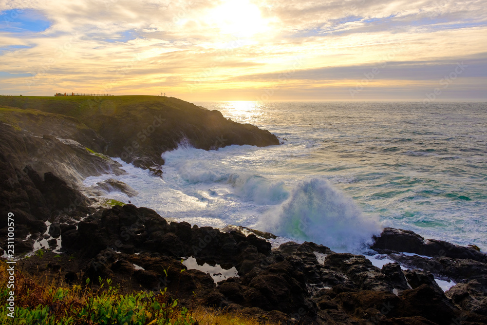 Fototapeta premium Ocean waves crashing onto the rocks in the sunset
