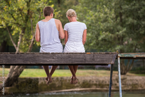 couple enjoying watermelon while sitting on the wooden bridge