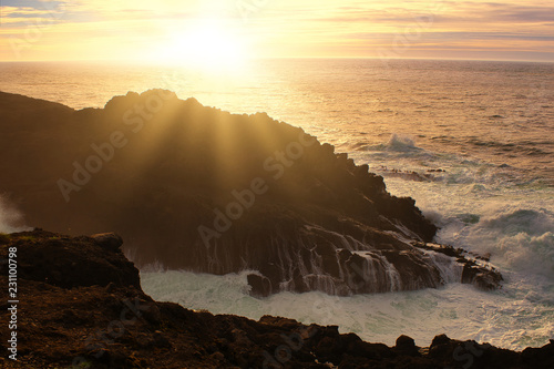 Ocean waves crashing onto the rocks in the sunset