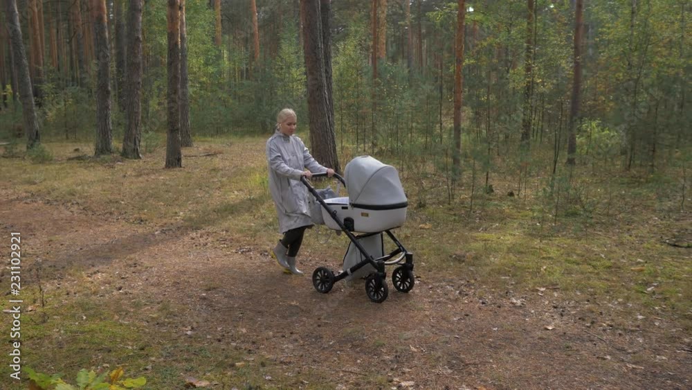 Young cute mom walking in the Park with a stroller. listening to music and dancing Young cute mom walking in the Park with a stroller. listening to music and dancing