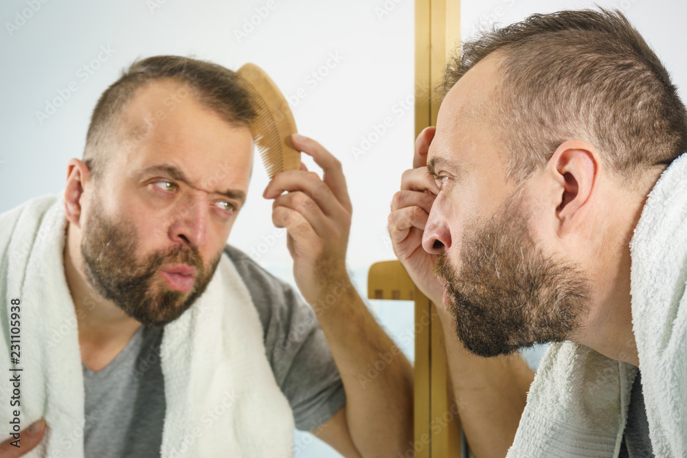 Obraz premium Man using comb in bathroom