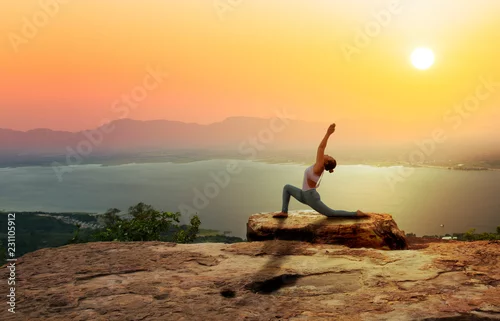 Obraz Kobiety praktyki joga na górze z zmierzchu lub wschodu słońca tłem