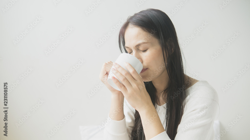 Beautiful woman lying in bed with a cup of coffee Beautiful woman lying in bed with a cup of coffee