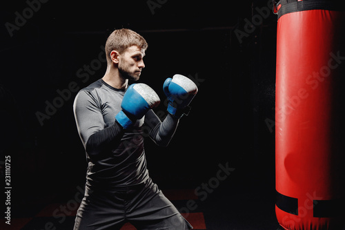 Male boxing in punching bag. Training Executes blows before fight. © Parilov