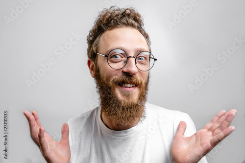 Friendly positive man wearing spectacles looking at camera with doubting, optimistic, questioning expression.