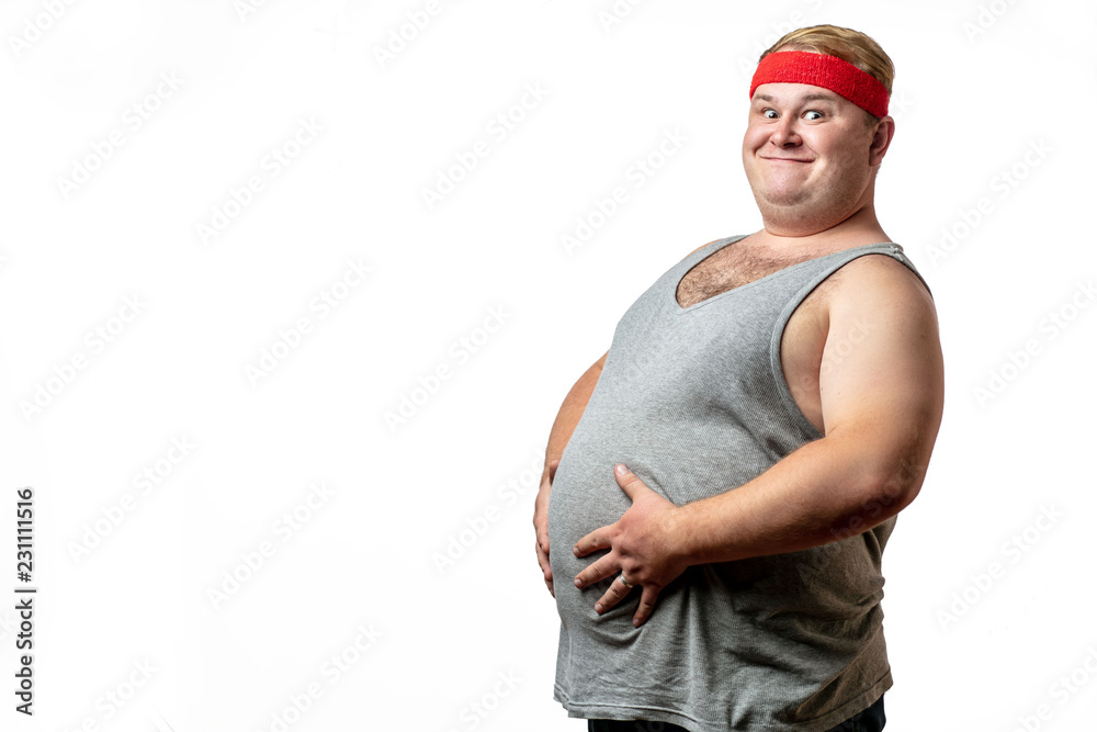 Funny picture of chubby cheerful caucasian man dressed in grey singlet with  red headband holding his big belly, posing isolated over white background  with copyspace. Stock Photo | Adobe Stock