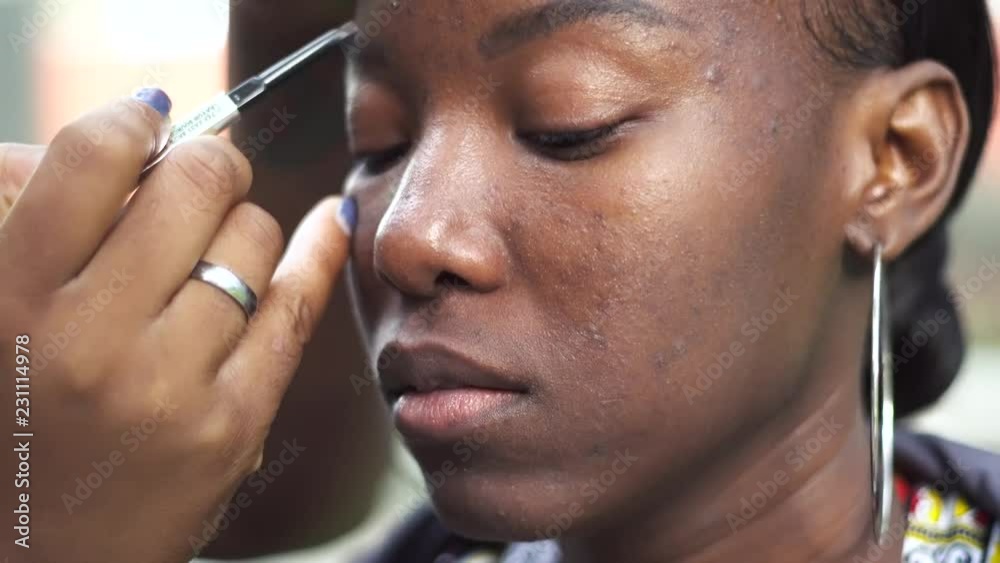 African american black woman is having her makeup done outdoors by a talented make up artist Behind the scenes shot before photo shoot tribal paint themed