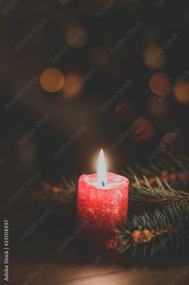 Red burning candle on Christmas tree background Red burning candle on Christmas tree background